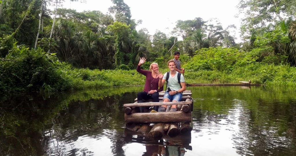 Viajeros saludando desde una balsa de madera en una cocha
